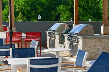 A patio with tables and chairs and an outdoor grill